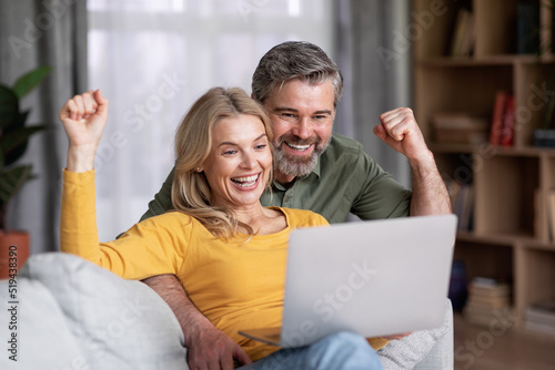 Online Lottery. Joyful Middle Aged Spouses Cheering Virtual Win With Laptop