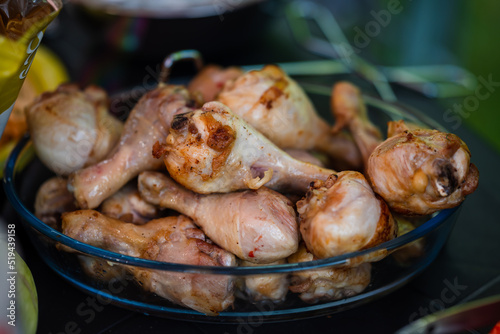 Fresh, juicy and fried chicken legs in a glass bowl on a black plastic table. Fresh and wholesome food. Small depth of field. Food in nature.