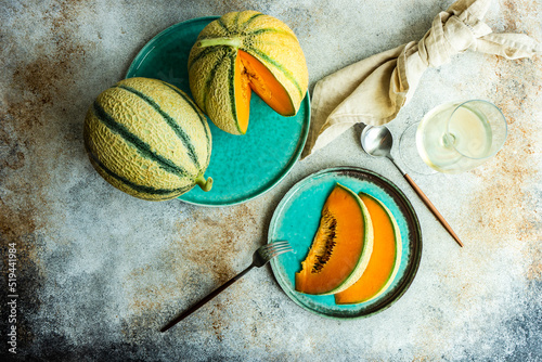 Overhead view of cantaloupe melons, slices of melon and a glass of white wine photo