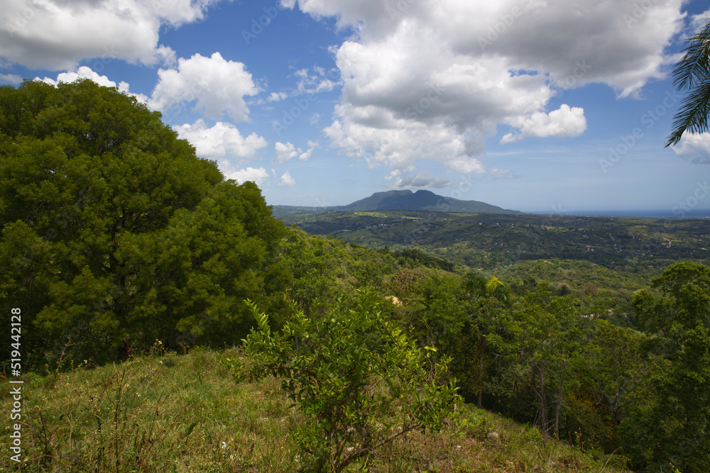 Blue sky with clouds over the mountains, green summer forest in Caribbean island