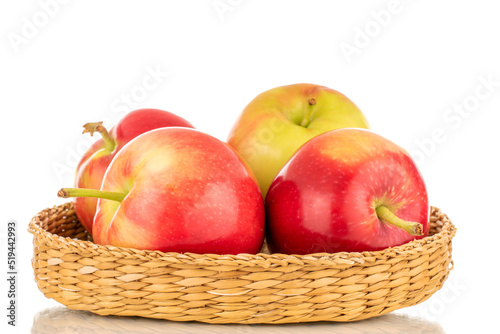 Several ripe sweet red apples in a straw plate, close-up isolated on a white background.