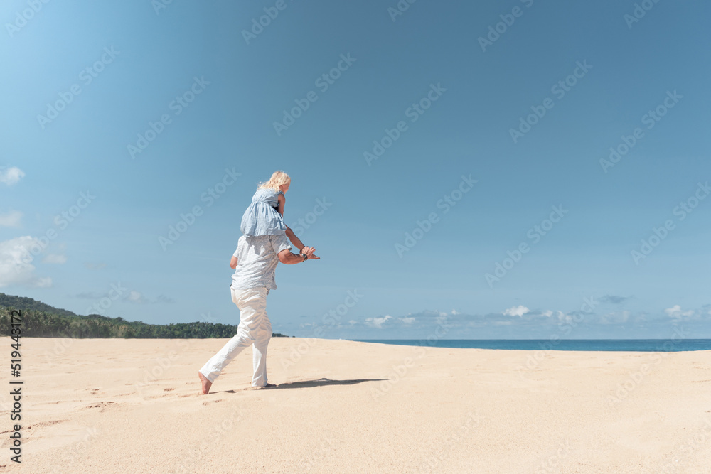 Padre e hija corriendo en playa del Caribe
