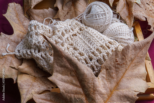 Autumn winter, balls of yarn and knitting on dry leaves