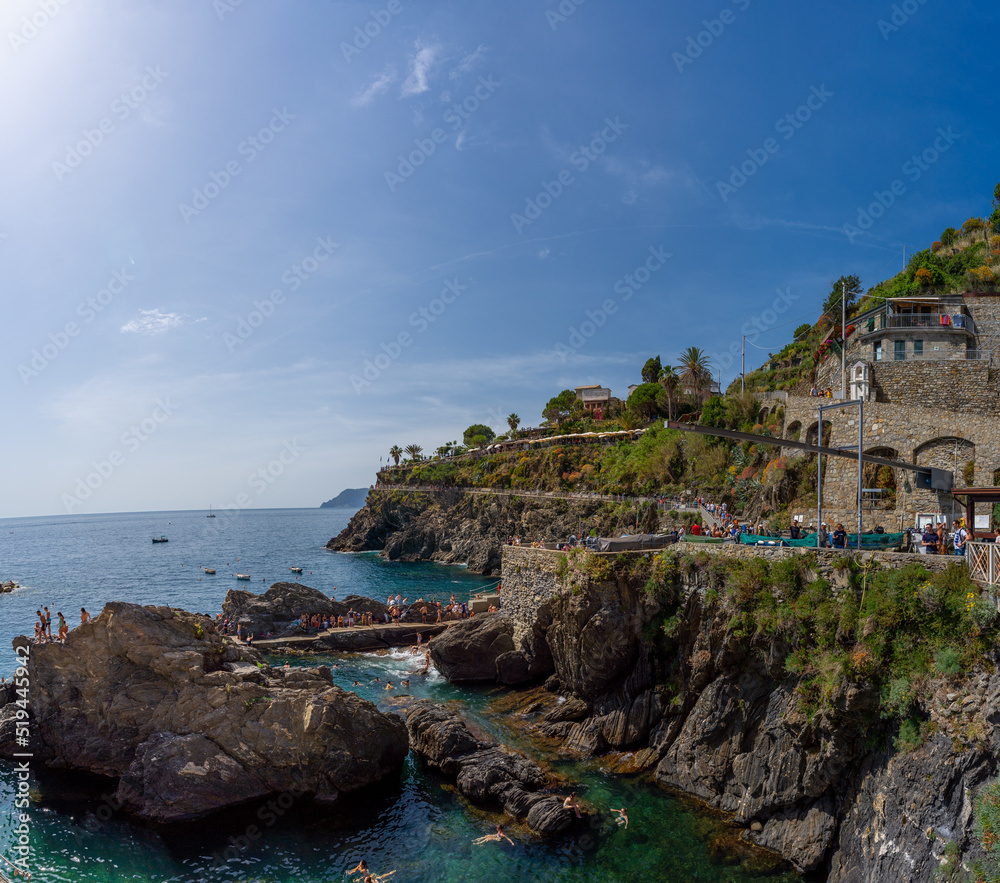 Aerial view to bay in Manarola, people having a bath, blue sky, Italy, Europe