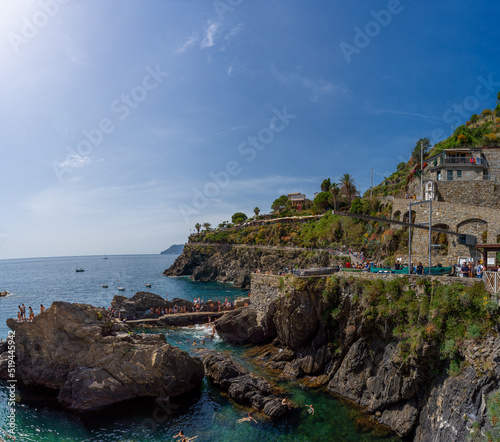 Aerial view to bay in Manarola, people having a bath, blue sky, Italy, Europe