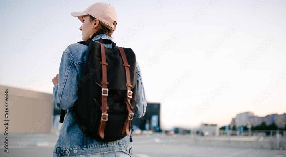 Tourist girl with her backpack looking at city landscape, back view Adventure and travel in the concept . Backpack rear view. Tourism in city.