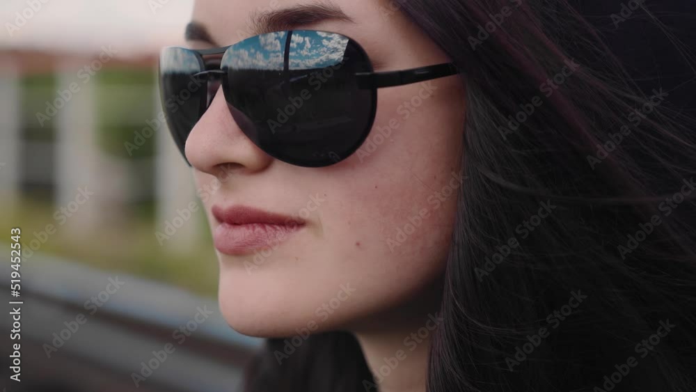 The blue sky is reflected in the glasses of the beautiful girl. The girl looks off into the distance. Cool young model The blue sky is reflected in the glasses of the beautiful girl. The girl looks off into the distance. Cool young model