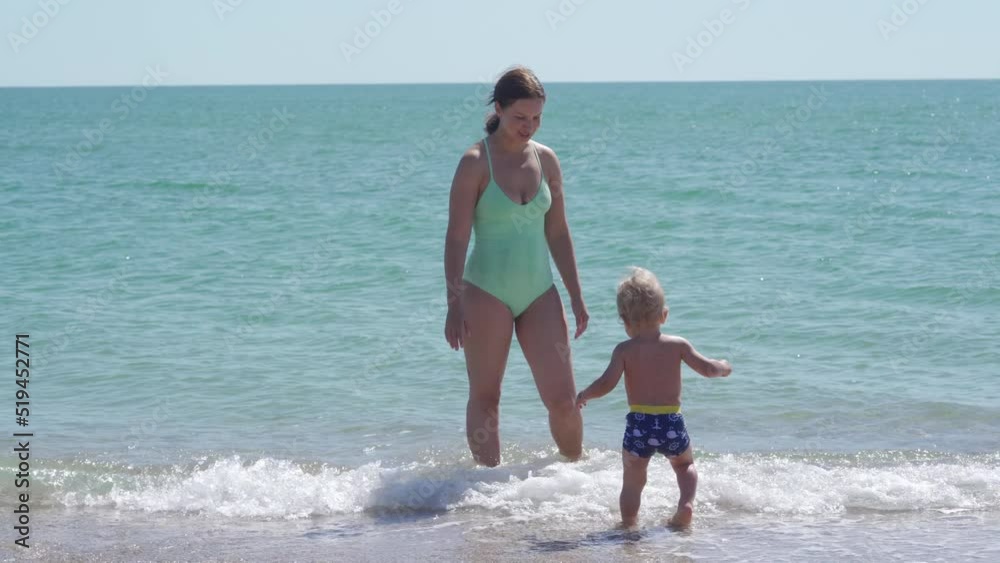 Mother with little cute child having fun playing on the beach, Joyful mother and baby son play at the edge of the sea surf on sand beach. Happy family holidays. Mother with little cute child having fun playing on the beach, Joyful mother and baby son play at the edge of the sea surf on sand beach. Happy family holidays.