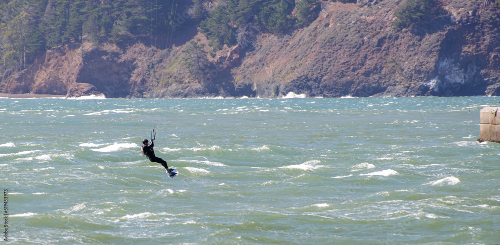 Kitesurfer riding over whitecaps on a very windy day