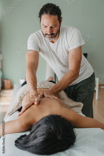 vertical photo of a masseur giving a massage to a patient lying on a massage table. photo
