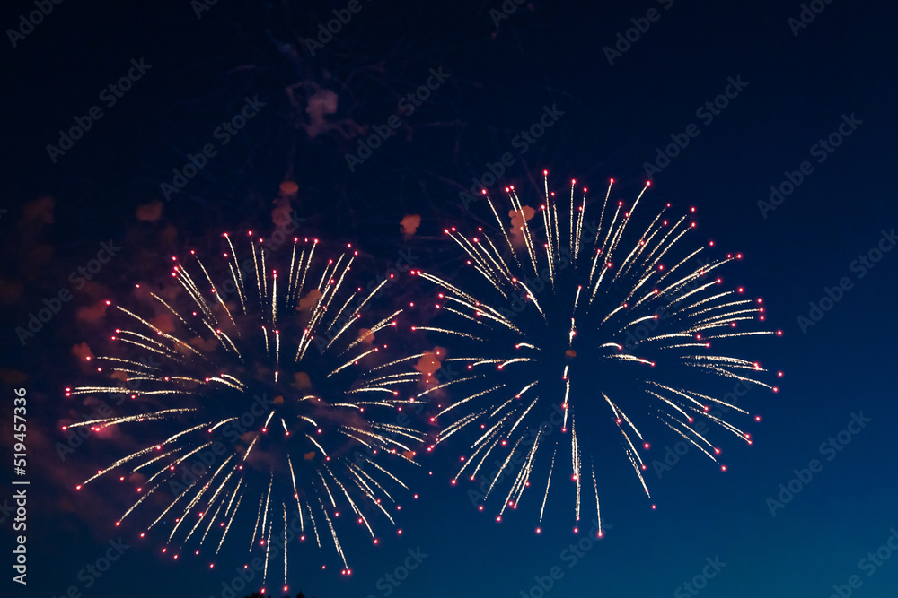 Colorful firework over the blue sky at night, White and red. Amateur photo. Noise. Grain