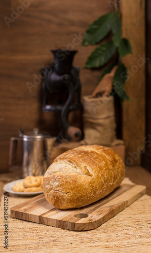 Natural fermentation bread and hand-cranked coffee grinder full of coffee beans and a small sack with a spoon at the bottom.