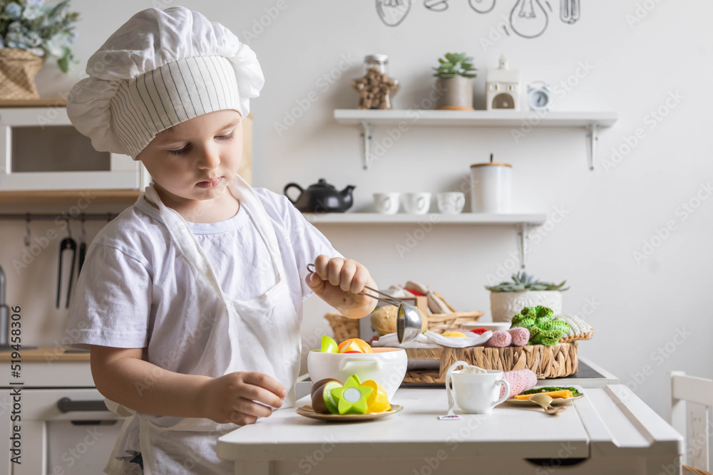 Cute baby boy chef uniform cooking playthings vegetable salad at childish kitchen enjoy childhood Cute baby boy chef uniform cooking playthings vegetable salad at childish kitchen enjoy childhood