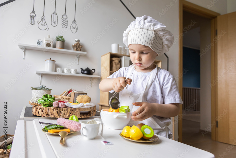 Cute baby boy chef uniform cooking playthings vegetable salad at childish kitchen enjoy childhood Cute baby boy chef uniform cooking playthings vegetable salad at childish kitchen enjoy childhood
