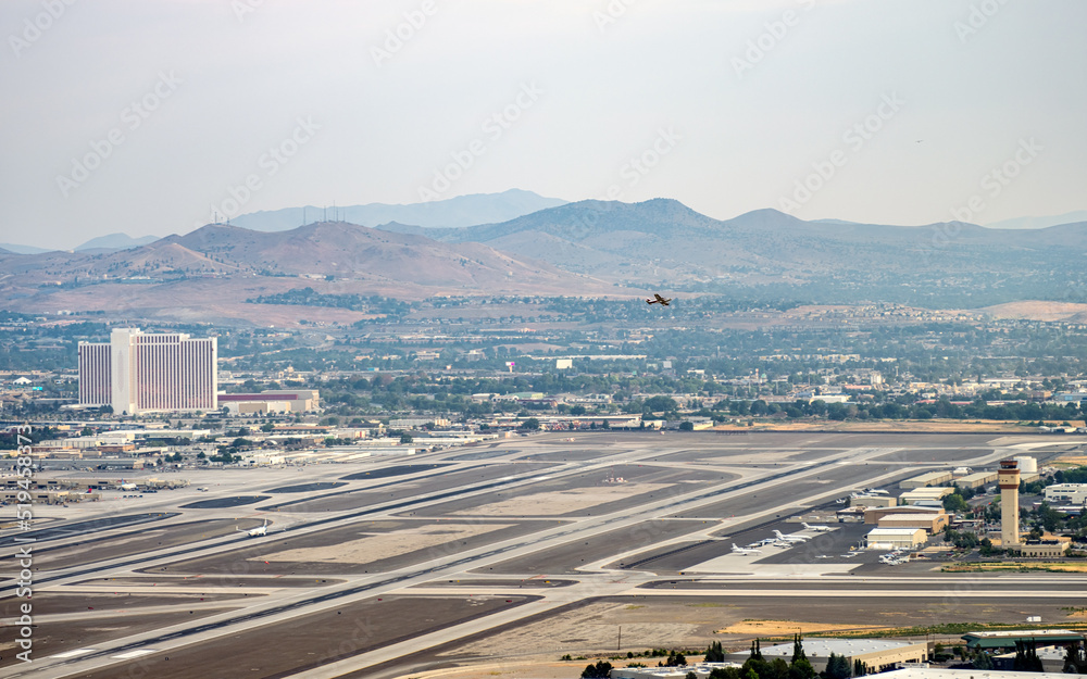 High angle view of the Reno Tahoe Airport and surrounding area with a small plane taking off and a Jet on the runway.