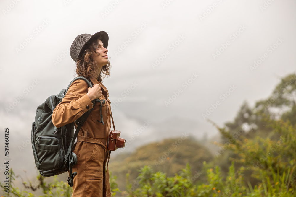 Side view of happy lady in hat standing and looking to the beautiful nature of the mountains in Africa, copy space