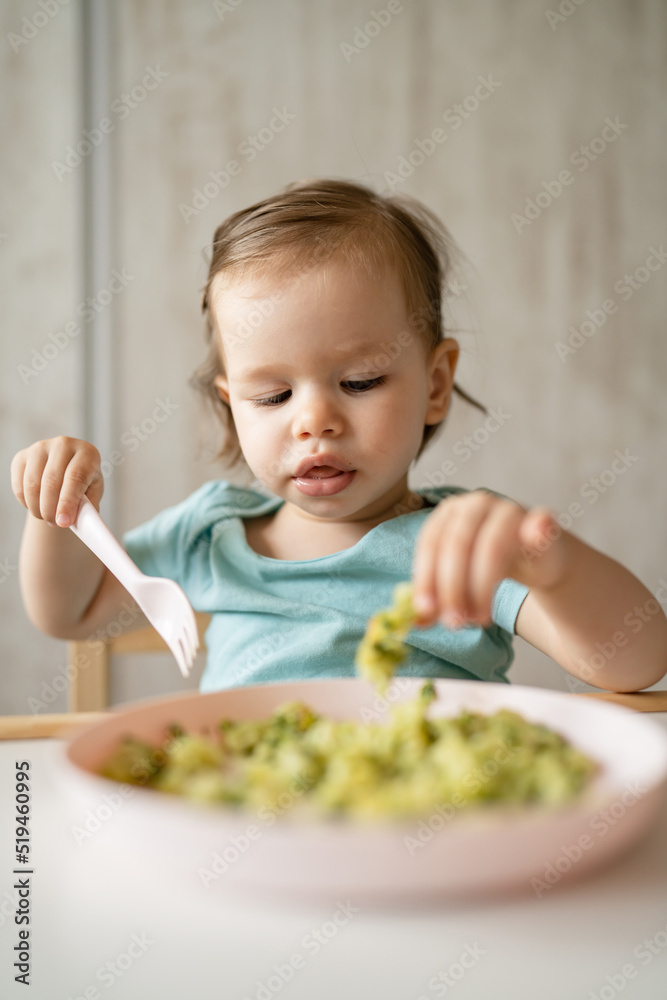 one girl small caucasian child one year old eat at the table at home one girl small caucasian child one year old eat at the table at home