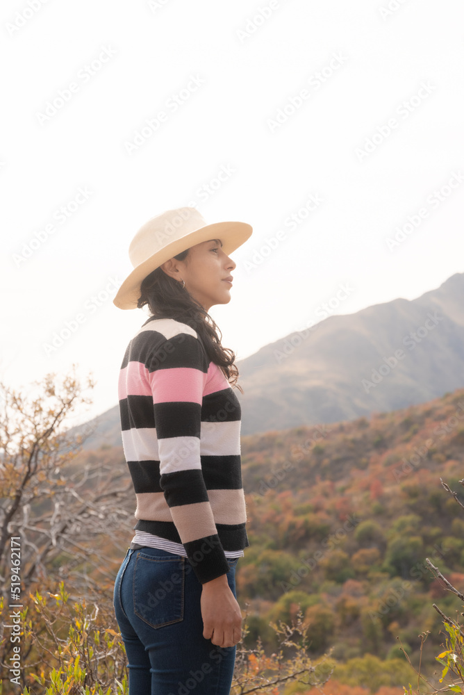 mujer con sombrero contemplando paisaje de montañas