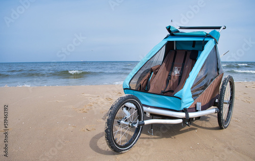 Empty bicycle trailer with front wheel at the beach
