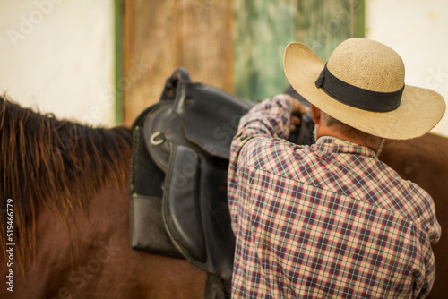 cowboy putting the saddle on his horse