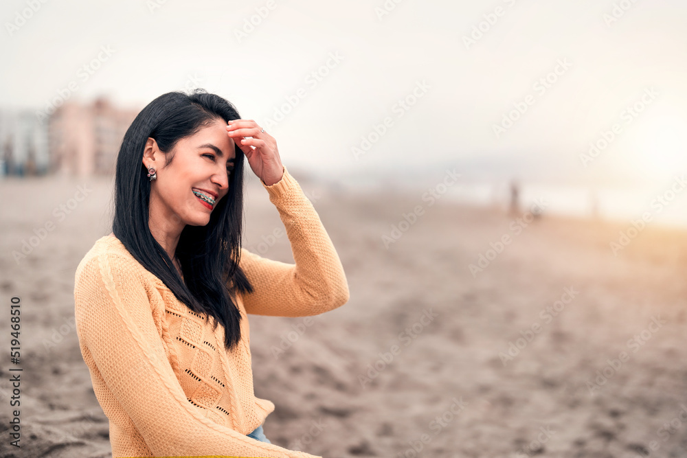 young latin woman with braces laughing on the beach portrait