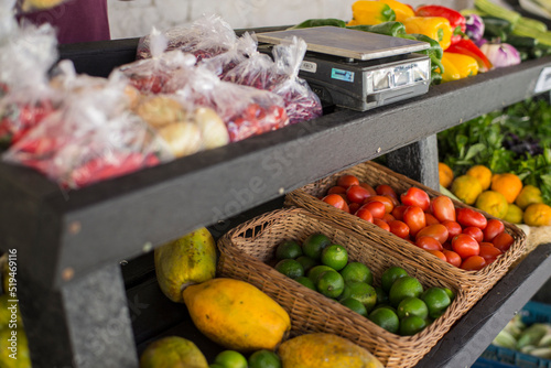 vegetable stand with peppers, tomatoes, eggplants and a scale.