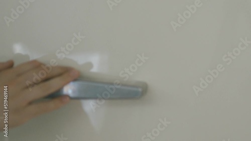 Detail of a hand opening a cream-colored Smeg refrigerator photo