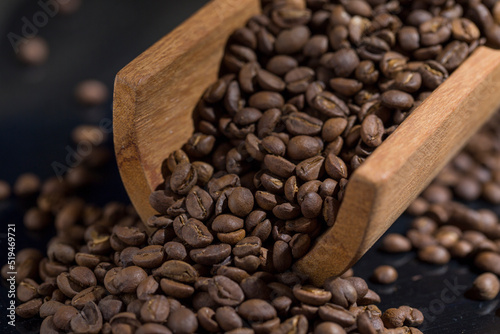 wooden spoon full of coffee beans on reflective surface
