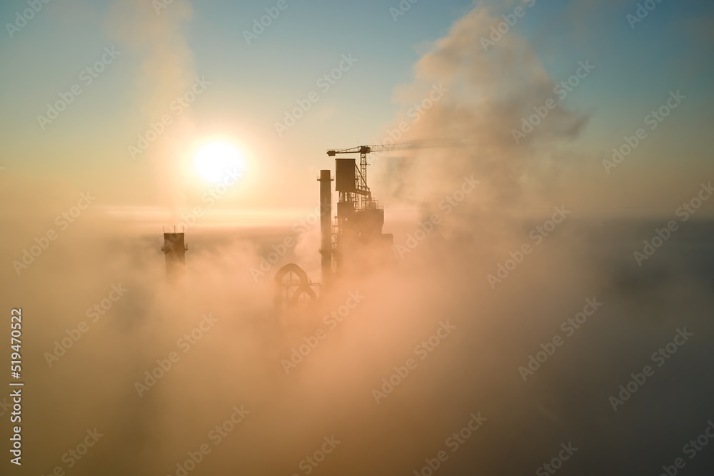 Aerial view of cement factory with high concrete plant structure and tower crane at industrial manufacturing site on foggy evening. Production and global industry concept Aerial view of cement factory with high concrete plant structure and tower crane at industrial manufacturing site on foggy evening. Production and global industry concept