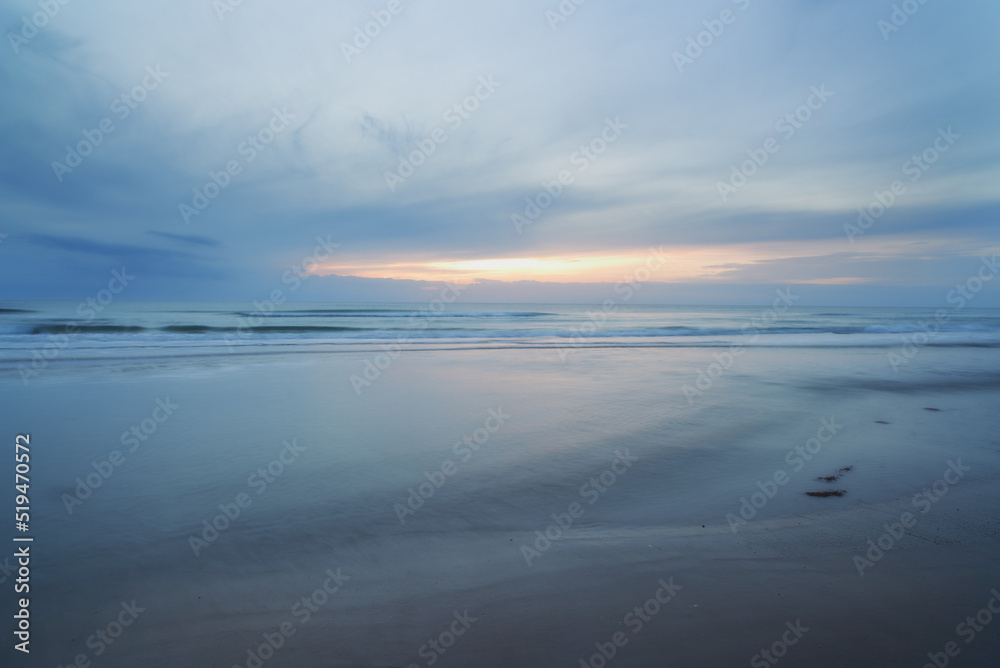 A beautiful, calm and quiet view of the beach and sunset sky over the horizon with copy space. A peaceful and scenic landscape of endless sandy water of the sea or ocean during low tide at dusk