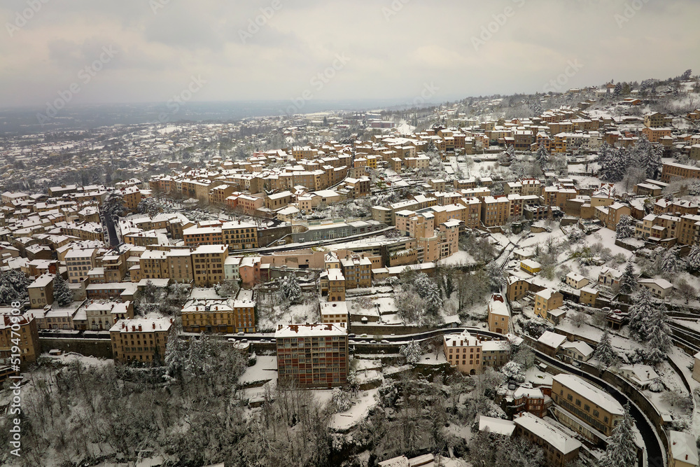 Aerial winter landscape of dense historic center of Thiers town in Puy-de-Dome department, Auvergne-Rhone-Alpes region in France. Rooftops of old buildings and narrow streets at snowfall