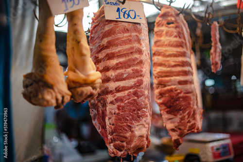 Pork ribs hung on steel hooks for sale in Amorn Nakhon Naklua Fresh Food Market, Thailand, July 26, 2022. photo