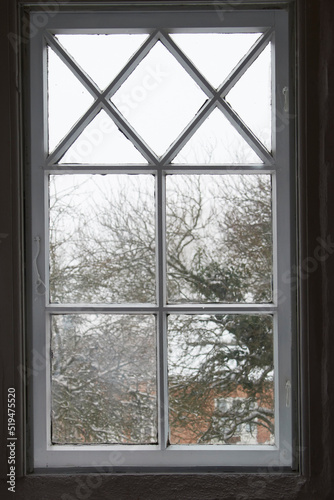 Closeup of a glass window from inside  looking out on cold weather in the morning. A wooden windowpane with bad insulation  shut and closed with a view of a winter scene with snow  frost and ice.