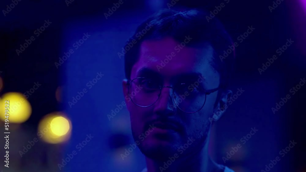 Close-up of a young man looking into the camera under a neon light. Night club Close-up of a young man looking into the camera under a neon light. Night club