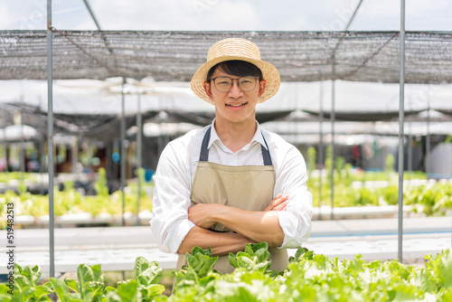 Hydroponic vegetable concept, Young Asian man standing with arms crossed in hydroponic salad farm