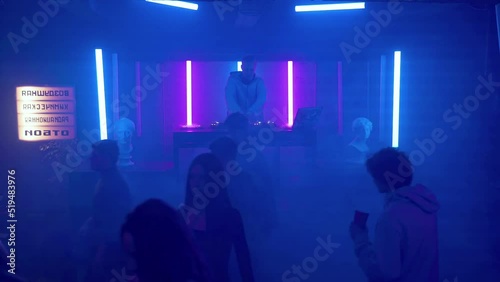 A crowd of people leaves the dance floor of a nightclub under the light of colored spotlights. One guy stays to dance. Night club