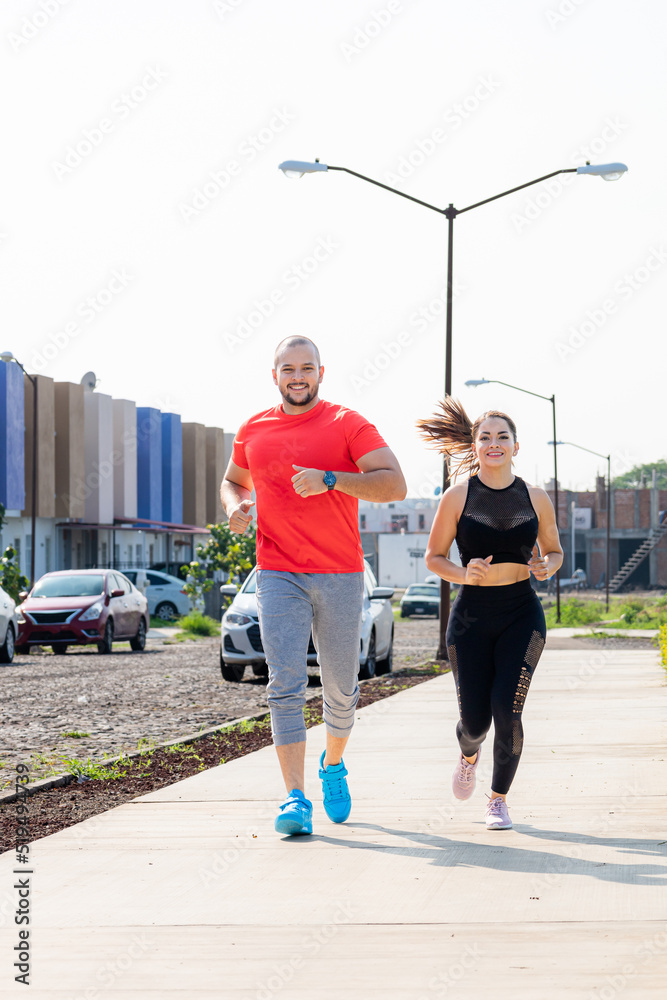 Fitness couple running outdoors at the park. Man and Woman in sportswear running in their neighborhood. Mexican runners.