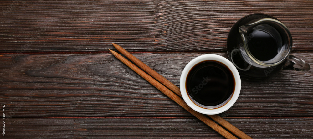 Soy sauce and chopsticks on dark wooden background with space for text, top view Soy sauce and chopsticks on dark wooden background with space for text, top view
