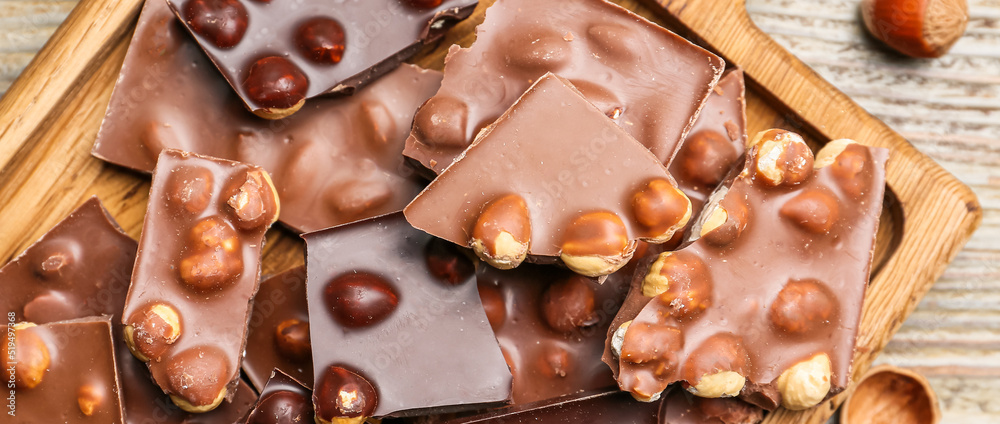 Pieces of tasty chocolate with hazelnuts on wooden table, top view Pieces of tasty chocolate with hazelnuts on wooden table, top view