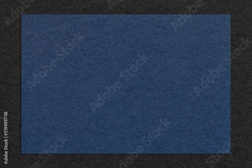 Texture of craft navy blue color paper background with black border, macro. Structure of vintage dense kraft cardboard