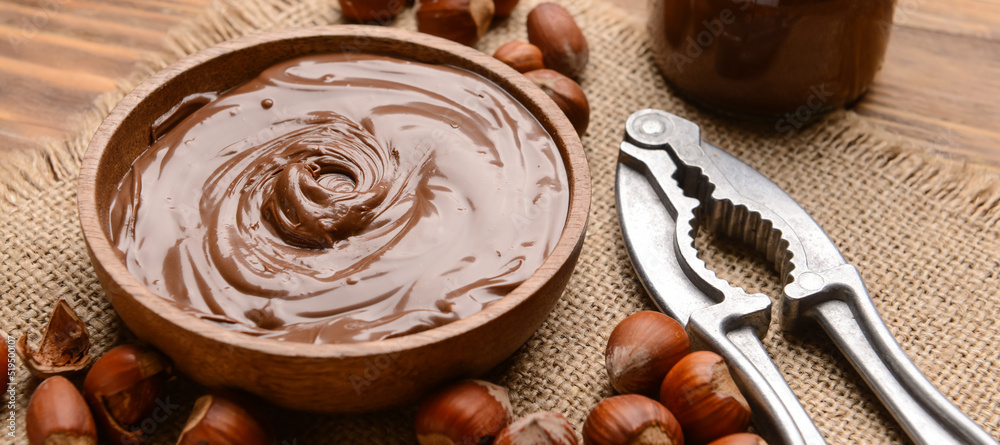 Bowl with tasty chocolate paste and hazelnuts on wooden background Bowl with tasty chocolate paste and hazelnuts on wooden background