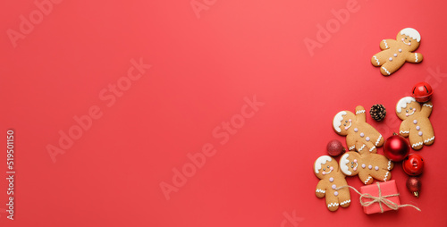 Tasty gingerbread cookies and Christmas decor on red background with space for text