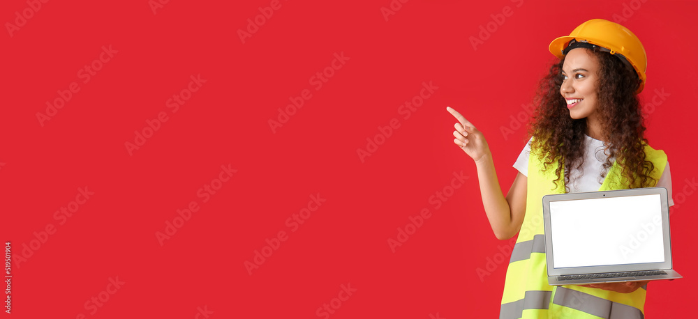 Young female architect with laptop pointing at something on red background with space for text Young female architect with laptop pointing at something on red background with space for text