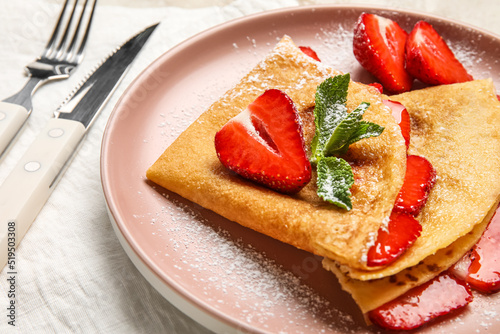 Plate of thin pancakes with strawberries and sugar powder on white background, closeup