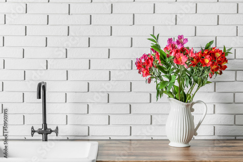 Vase with beautiful alstroemeria flowers near sink © Pixel-Shot