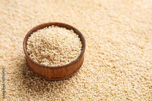 Wooden bowl with sesame seeds as background