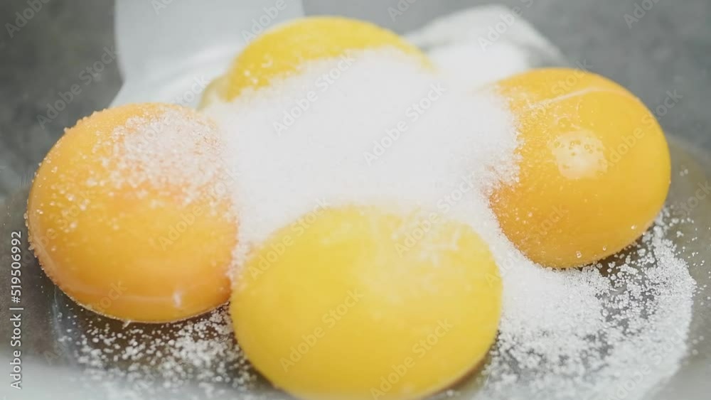 The confectioner adding sugar to yolks into a glass bowl.
The confectioner adding sugar to yolks into a glass bowl.