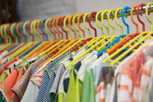 Line of multi colored clothes on plastic hangers in store. Sale