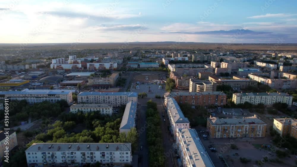 Aerial view from a drone of the small town of Balkhash on the shore of the lake. Low houses are painted in different colors, wide alleys, green trees grow. Cars are driving along the road. The clouds Aerial view from a drone of the small town of Balkhash on the shore of the lake. Low houses are painted in different colors, wide alleys, green trees grow. Cars are driving along the road. The clouds