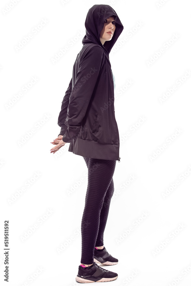 Full Length Portrait of Sportive Caucasian Female Athlete Posing In Black Hoody and Sexy Fitness Outfit While Posing With Crossed Hands Against White Background